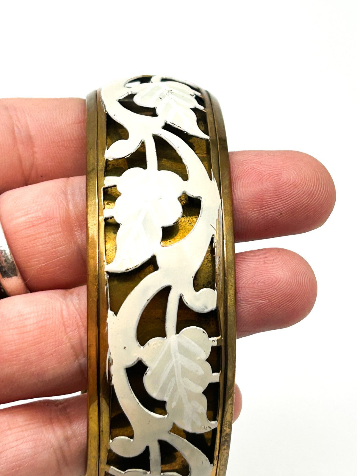 Brass tone bangle with white floral openwork metal design