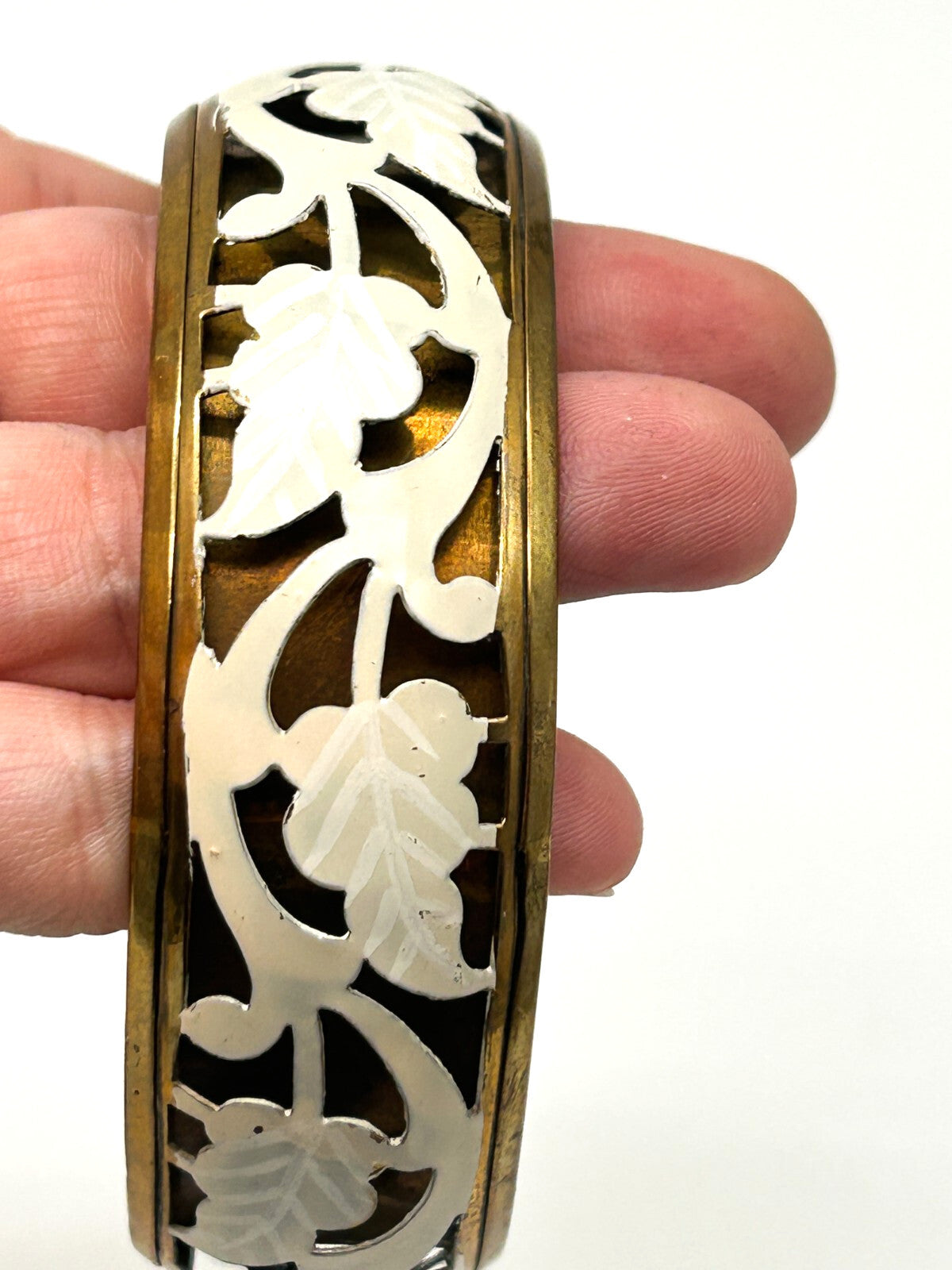 Brass tone bangle with white floral openwork metal design